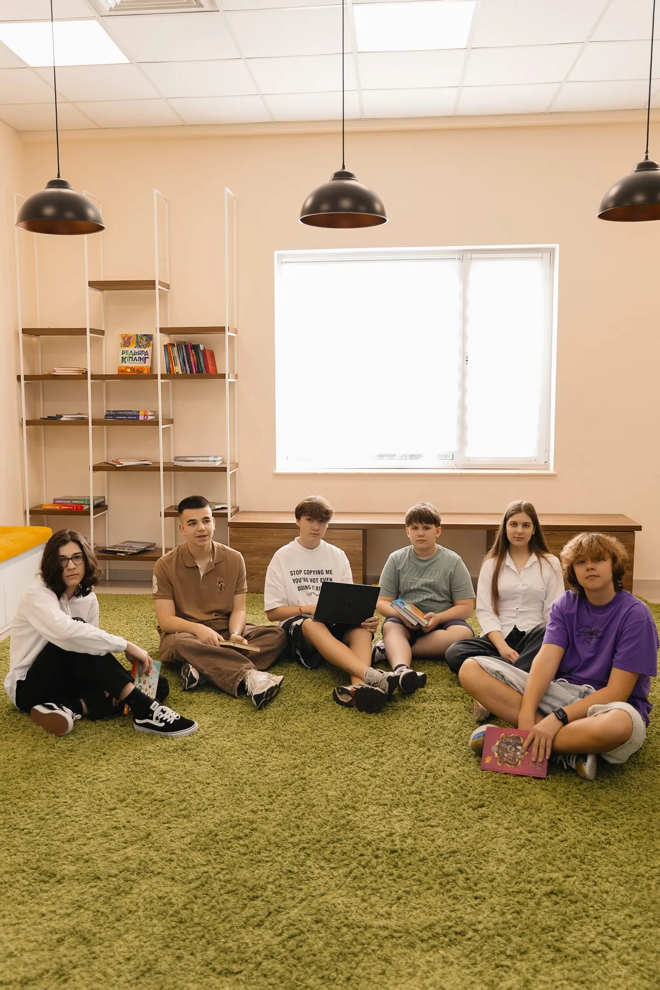 Підлітки з книжками у шкільній бібліотеці